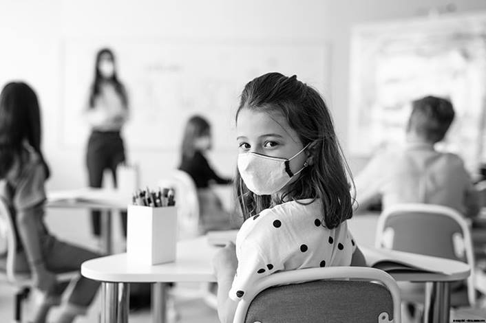 Masked child sitting in classroom